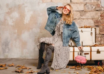 Mulher elegante usando jaqueta jeans oversized e vestido floral com botas de cano alto, estilo para São João 2025.