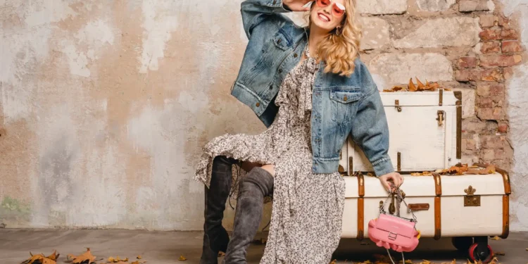 5 tendências de moda para o São João 2025 1 Mulher elegante usando jaqueta jeans oversized e vestido floral com botas de cano alto, estilo para São João 2025.