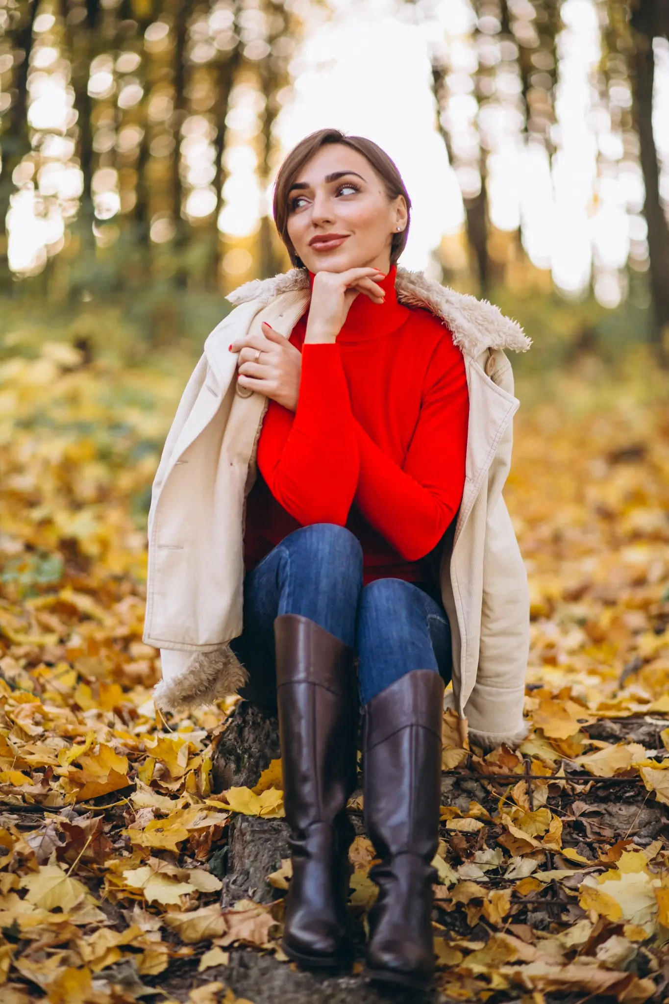Mulher usando look de outono com suéter vermelho e botas no parque