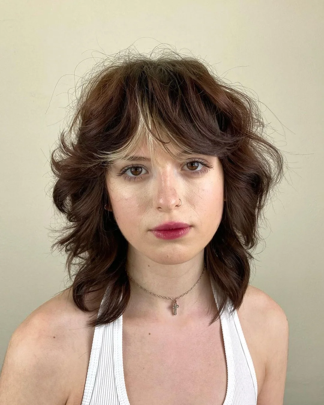 Corte shaggy hair com estilo long bob em cabelo castanho com mechas claras na franja.