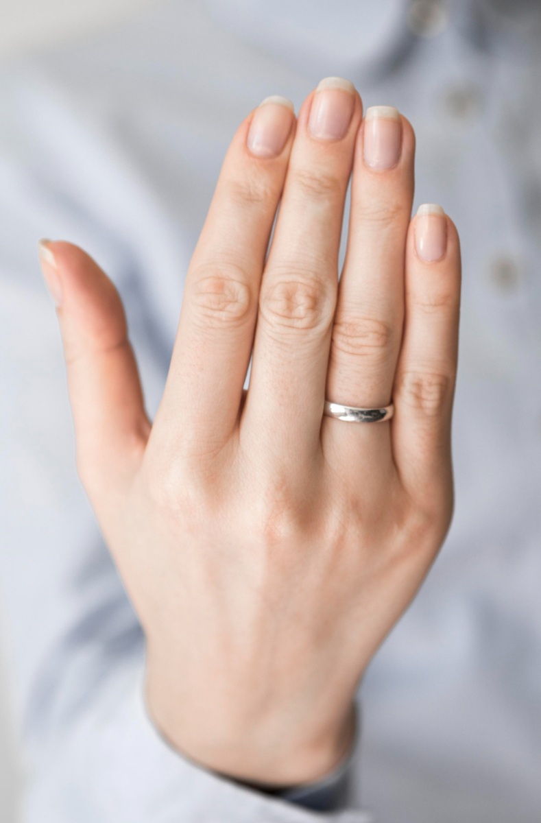 Mão feminina mostrando unhas naturais e saudáveis.