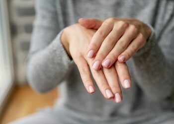 Mãos femininas cuidadas com unhas feitas e esmaltadas.