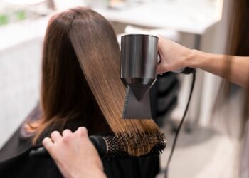 Secagem e alisamento do cabelo com secador e escova.