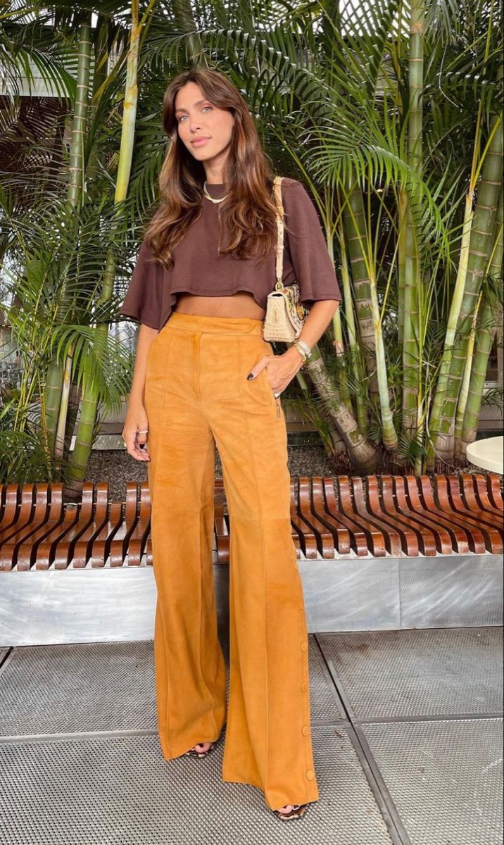 Mulher usando blusa marrom e calça amarela, destacando a combinação perfeita de cores para o inverno.