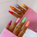Unhas decoradas com esmaltação colorida vibrante em tons arco-íris