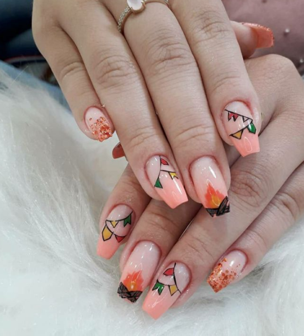 Unhas decoradas com bandeirinhas coloridas e pequenos desenhos de fogueira.