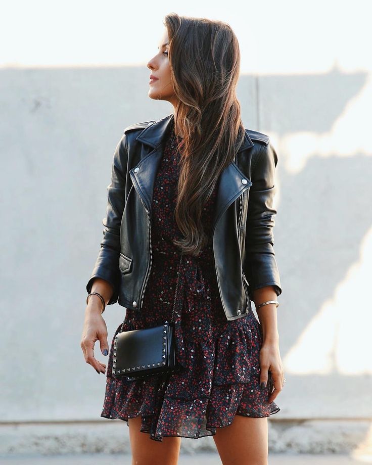 Mulher usando jaqueta de couro preta com vestido estampado em look casual