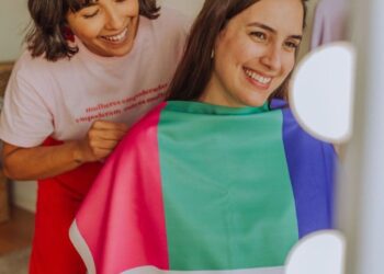 Consultoria de imagem com foco na escolha da paleta de cores, mostrando uma cliente sorrindo enquanto experimenta uma capa colorida.