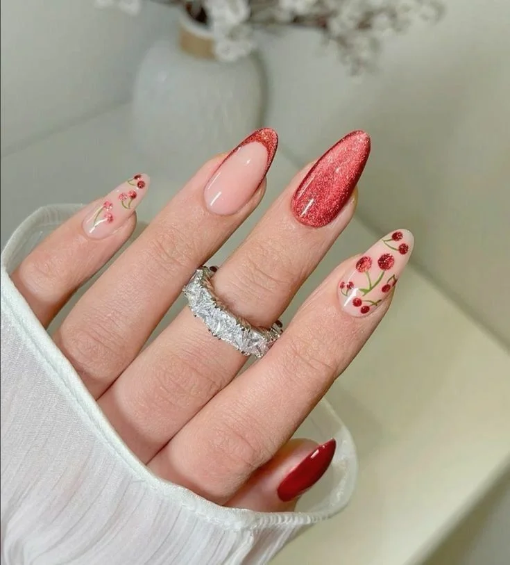 Unhas decoradas com flores delicadas e brilho vermelho, perfeitas para um estilo romântico.