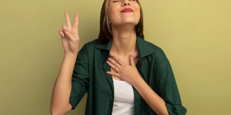 Mulher feliz com gesto de vitória, demonstrando autoconfiança, com a mão no peito e sorrindo