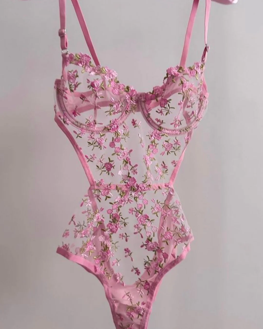 Body cor-de-rosa transparente com flores bordadas, estilo delicado e feminino.
