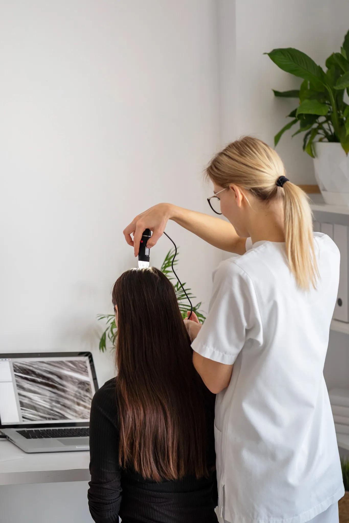 Mulher consultando um especialista em cuidados capilares, com dermatologista analisando o couro cabeludo.