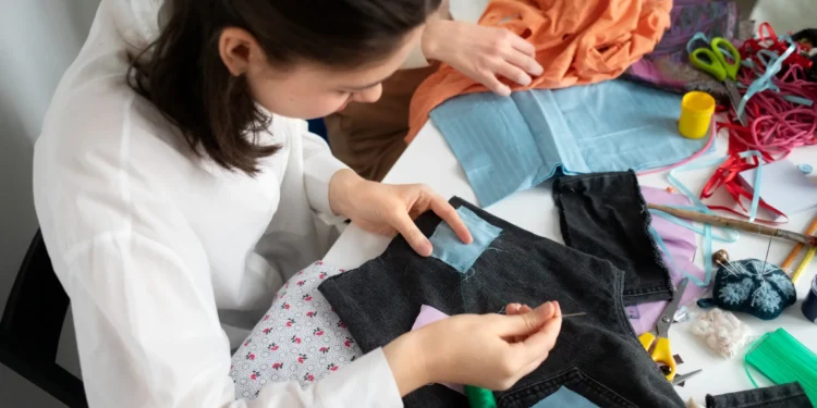 Pessoa costurando retalhos em peça jeans para customização de roupas juninas