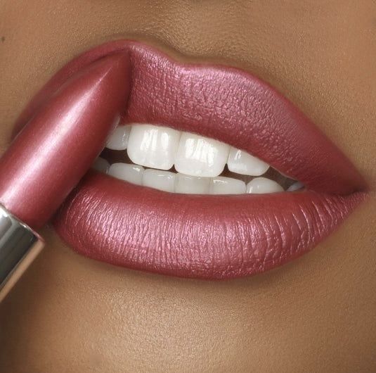Lábios com batom rosa metálico sendo aplicados com acabamento cintilante