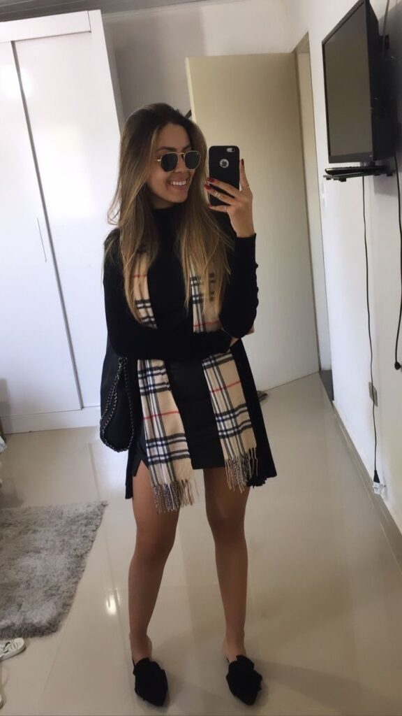 Mulher usando cachecol xadrez em look preto estiloso para o inverno junino