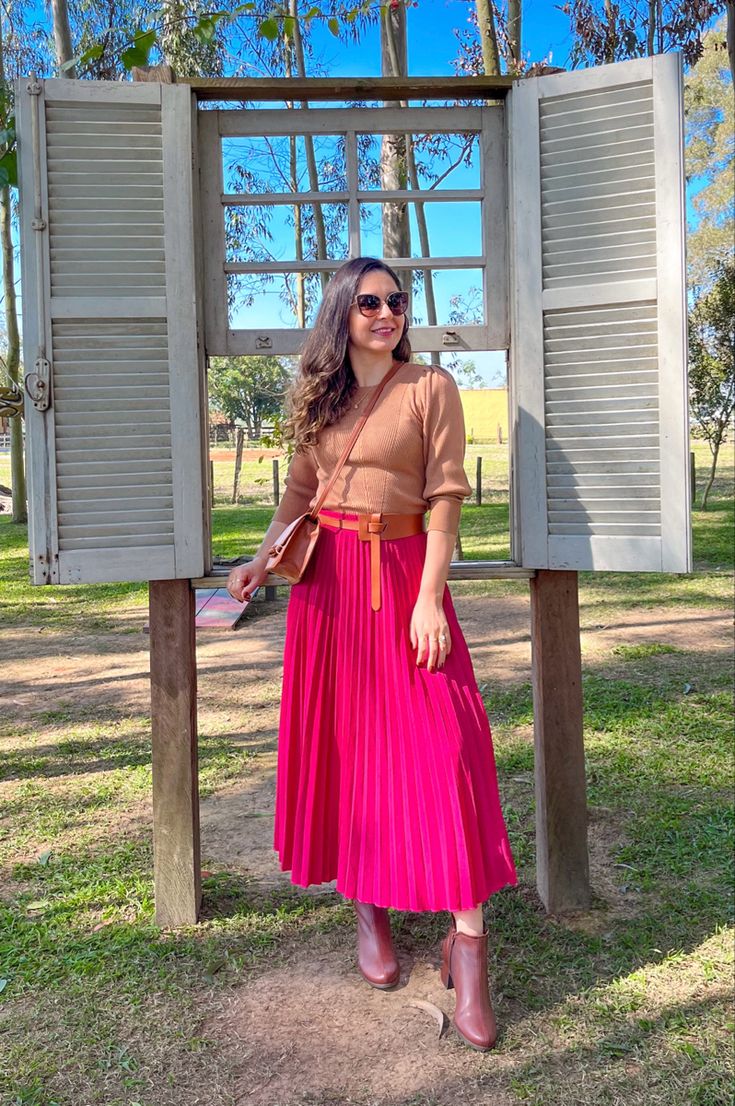 Mulher usando blusa marrom e saia rosa, demonstrando a combinação de cores perfeita para o inverno.