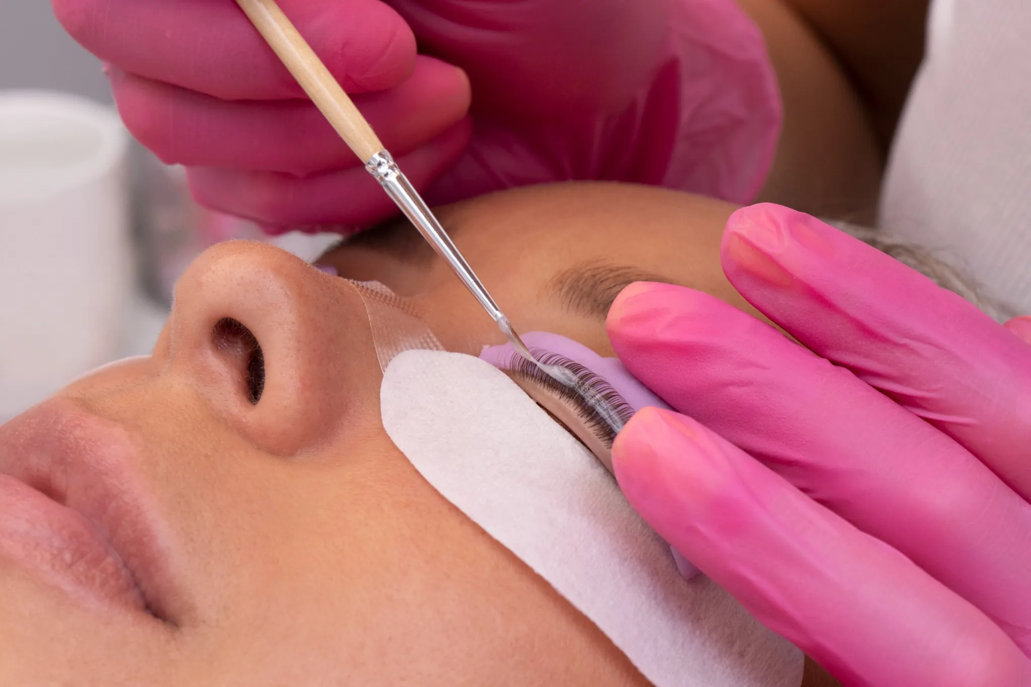 Profissional aplicando lifting de cílios com pincel de precisão
