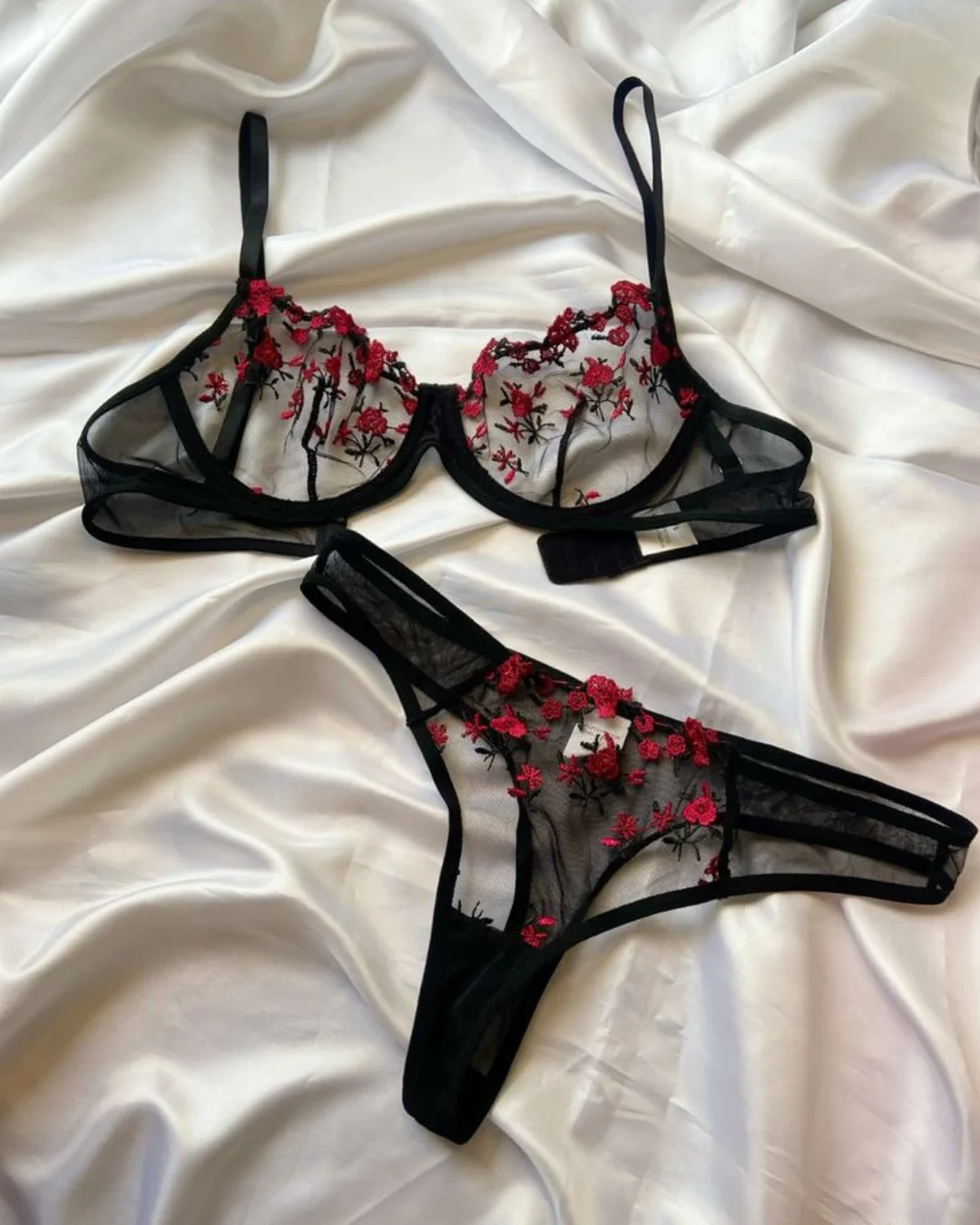 Conjunto de lingerie preto com detalhes florais vermelhos.