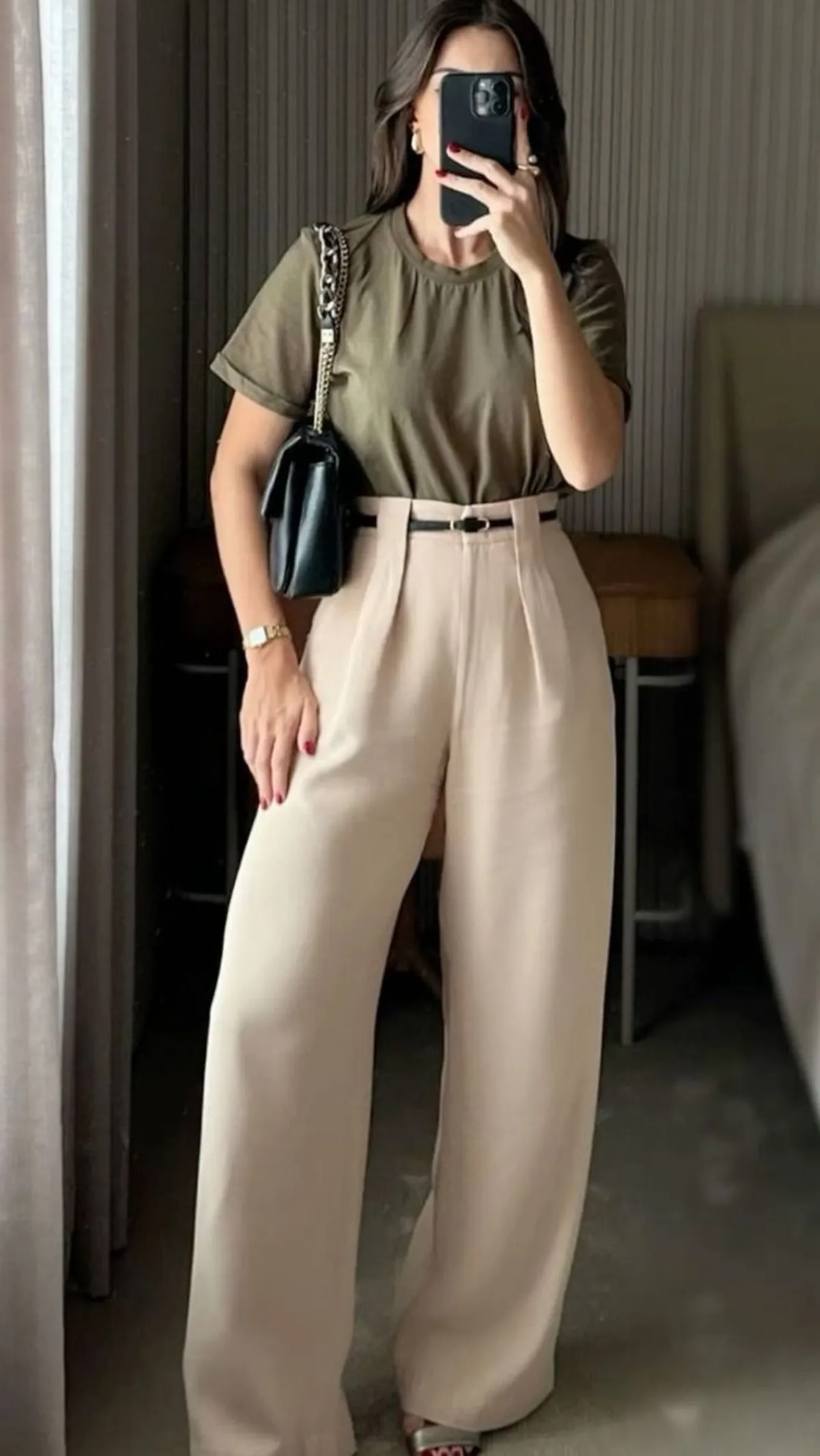 Mulher com calça de alfaiataria clara e blusa básica em tom terroso