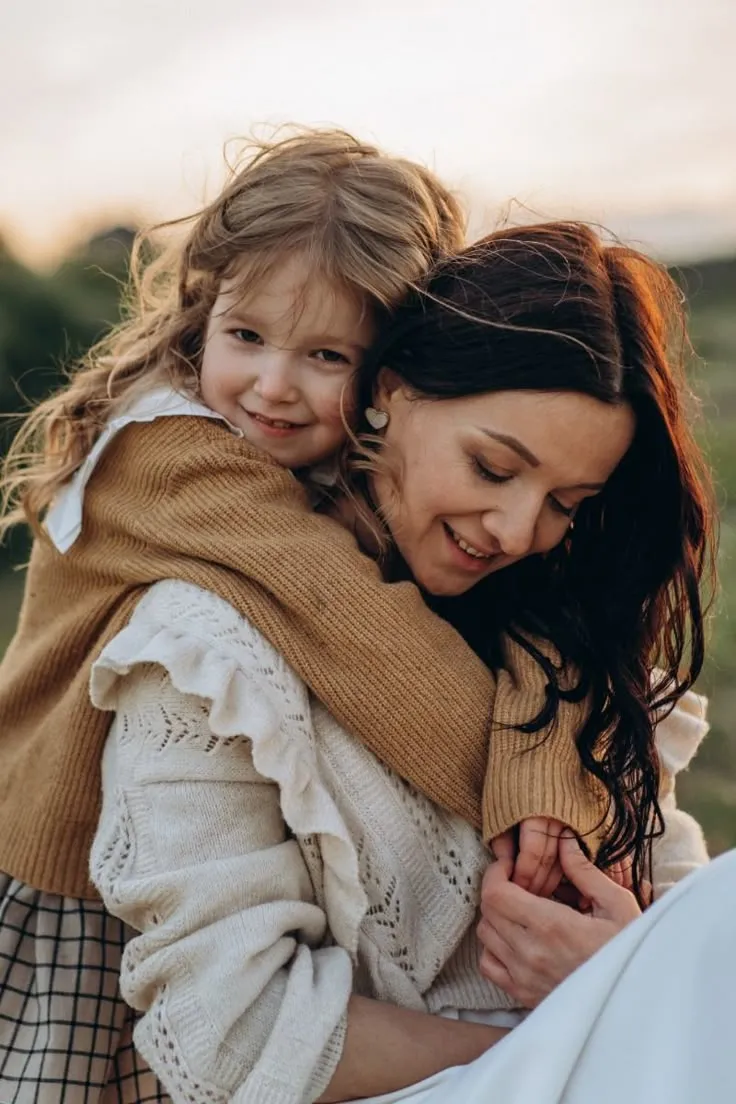 Mãe e filha se abraçando ao ar livre, transmitindo amor e conexão.
