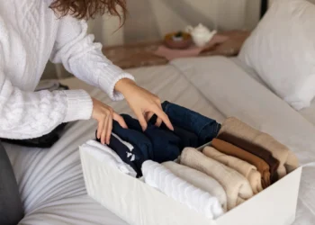 "Pessoa dobrando roupas e organizando peças básicas para looks versáteis.