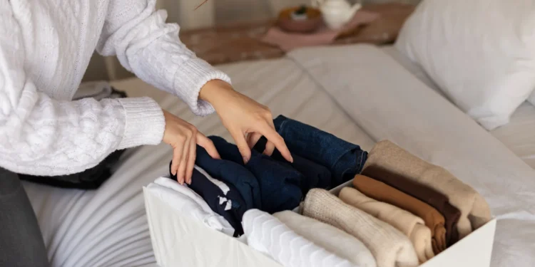 Montando looks com peças básicas: dicas para arrasar com o essencial 1 "Pessoa dobrando roupas e organizando peças básicas para looks versáteis.