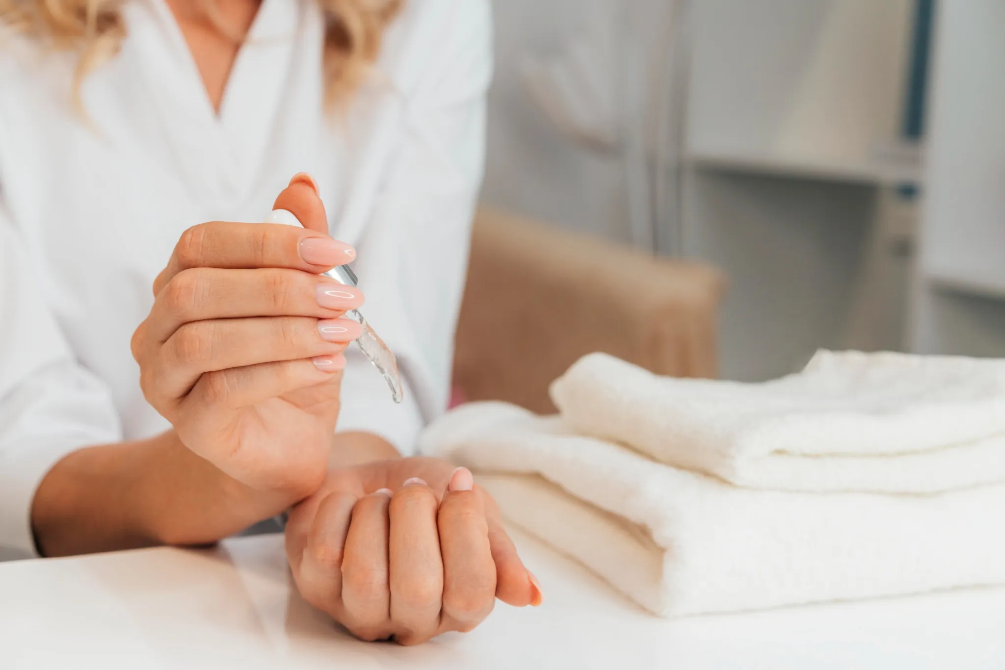 Mulher aplicando óleo secante nas unhas após a manicure