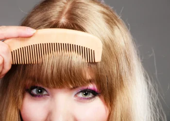 Mulher com franja sendo penteada com um pente de madeira.