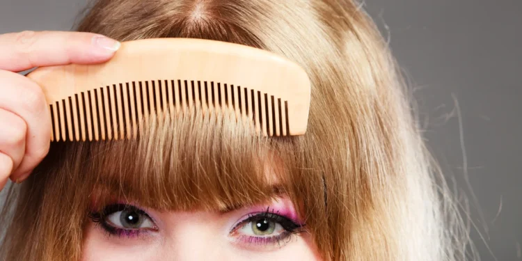 As franjas que estão bombando entre as famosas em 2025 1 Mulher com franja sendo penteada com um pente de madeira.