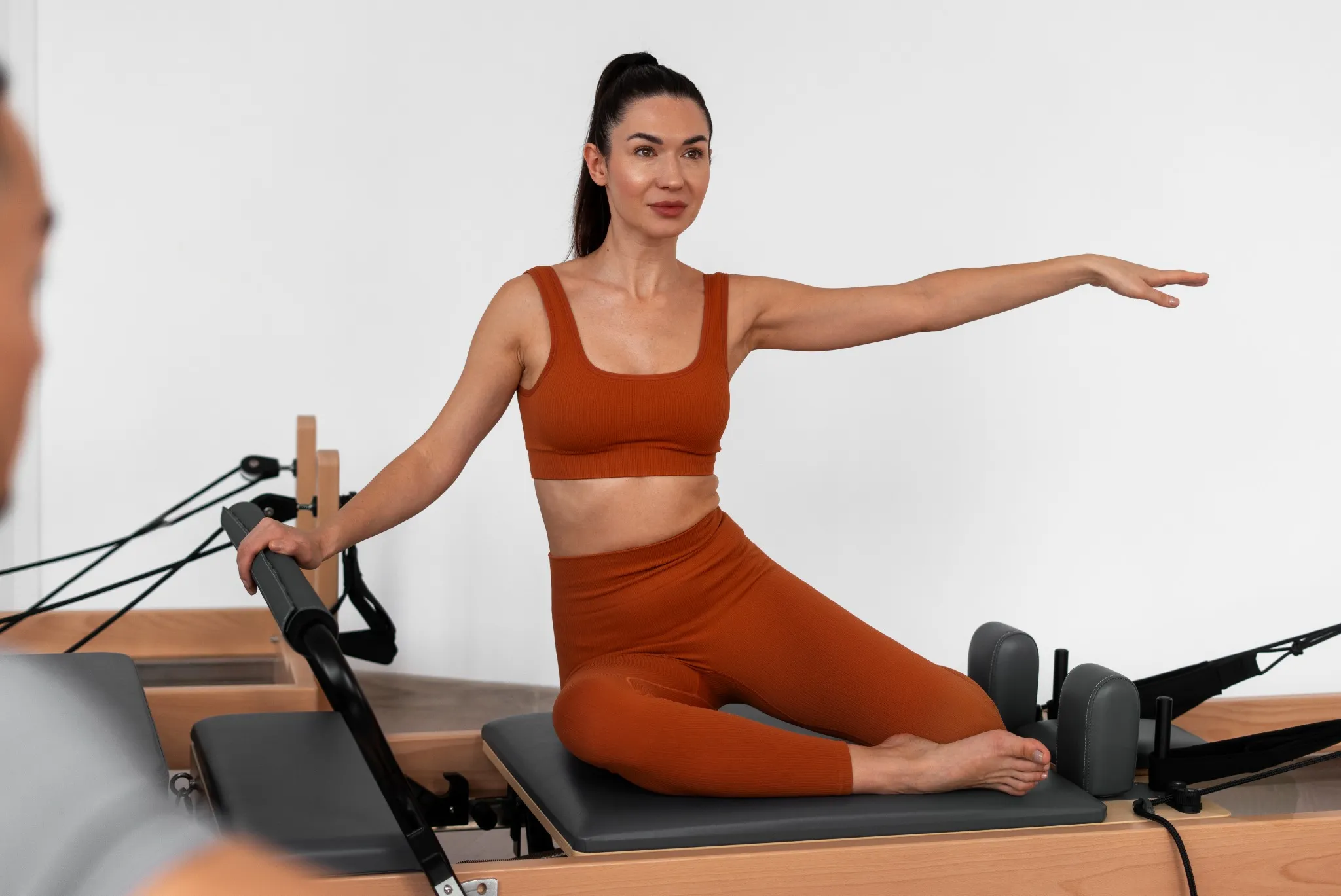 Mulher praticando Pilates em aparelho, com foco no fortalecimento do centro do corpo e postura.