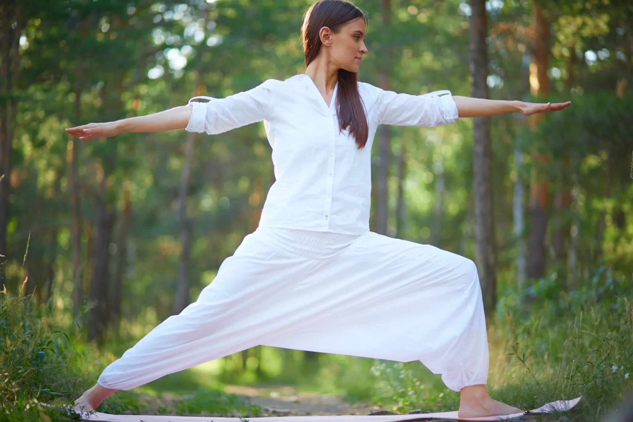  Mulher praticando Tai Chi ao ar livre, em um ambiente natural, com foco no equilíbrio e nos movimentos suaves.