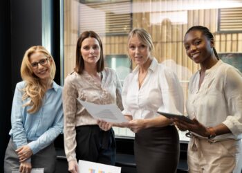 Mulheres sorrindo e colaborando, representando o empoderamento feminino no trabalho
