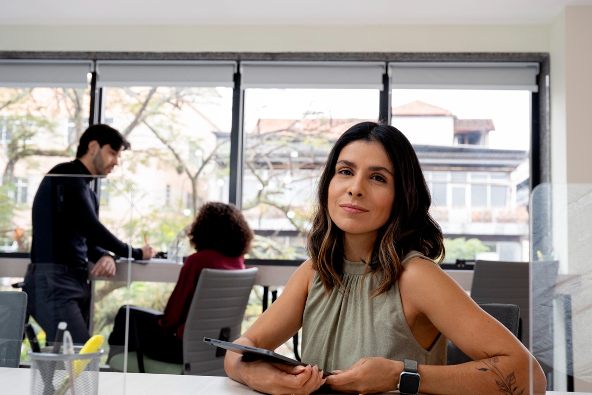 Mulher sorrindo em ambiente de trabalho, representando estratégias de destaque profissional
