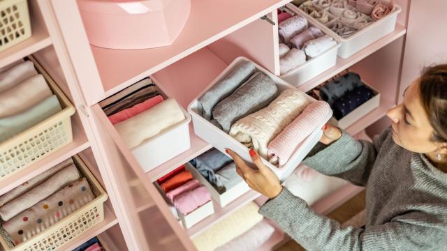 dobrar roupas deixa seu armário organizado, com peças de roupas em caixas e prateleiras organizadas. 