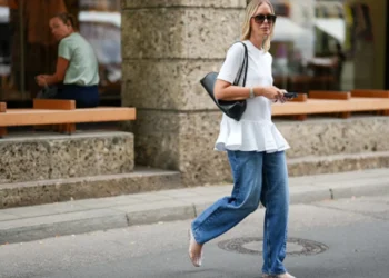 Mulher com blusa longa e jeans, representando a tendência Y2K, caminhando pela rua.