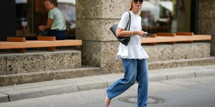 Tendência Y2K: blusas longas voltam com tudo e combinam perfeitamente com jeans slim 1 Mulher com blusa longa e jeans, representando a tendência Y2K, caminhando pela rua.