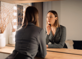 Mulher se olhando no espelho enquanto avalia seu visual.