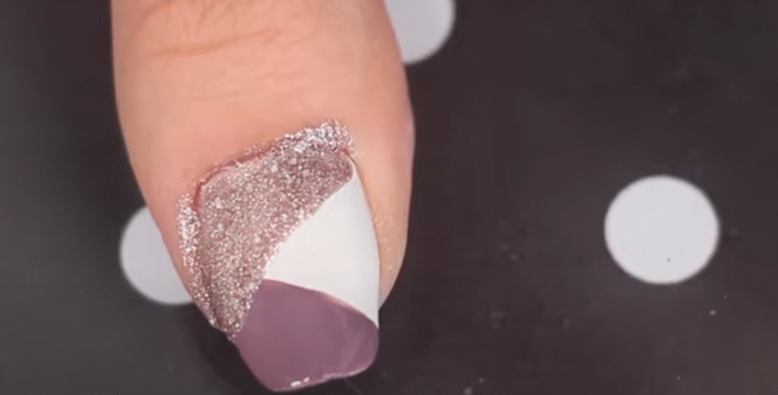Unha decorada com nail art geométrica em rosa queimado, branco e glitter.