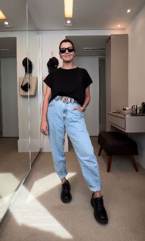 Mulher com look básico estiloso usando calça jeans dobrada e camiseta preta