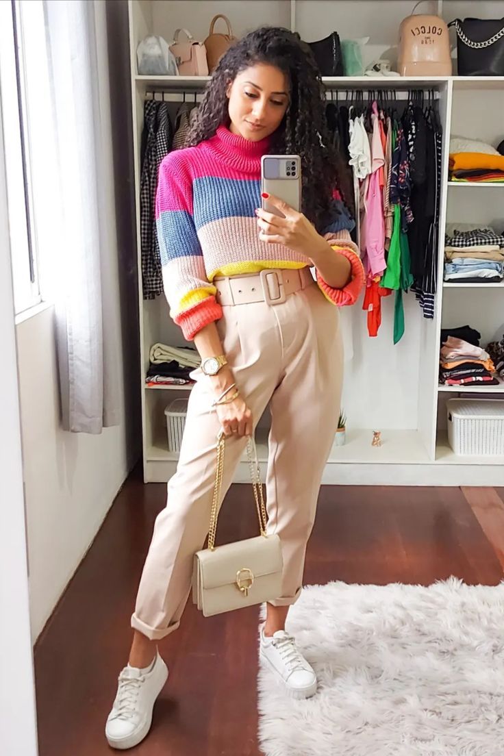 Look com tricô colorido, calça de alfaiataria bege, tênis branco e bolsa clara.