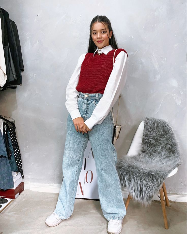 Look com camisa branca, colete vermelho e calça jeans larga.