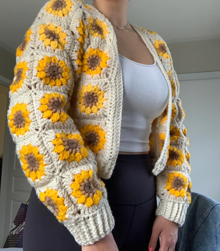 Cardigã de crochê com flores amarelas e marrons, uma peça de roupa versátil e estilosa.