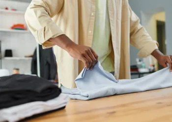 Pessoa dobrando uma camiseta, utilizando o método KonMari para organizar roupas.
