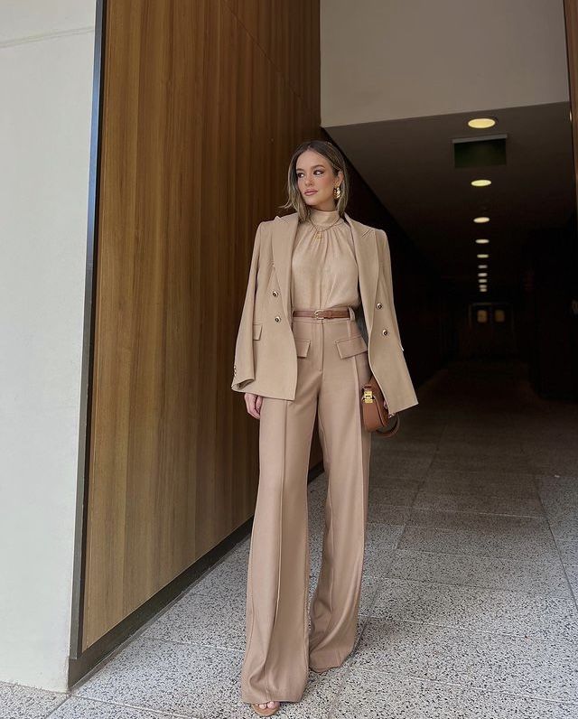 Mulher usando look monocromático bege com blazer e calça de alfaiataria