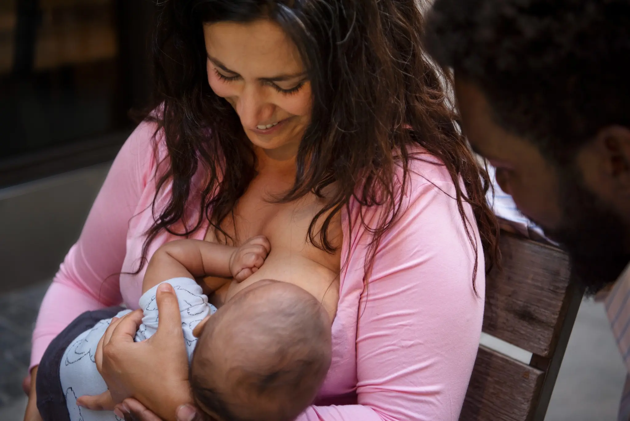 Mãe sorridente amamentando seu bebê, ilustrando o momento de conexão e carinho.