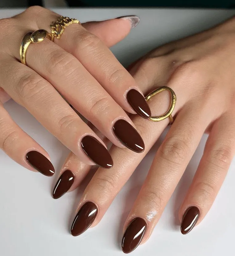 Unhas com esmalte marrom chocolate, criando um visual elegante e aconchegante, ideal para os dias frios.