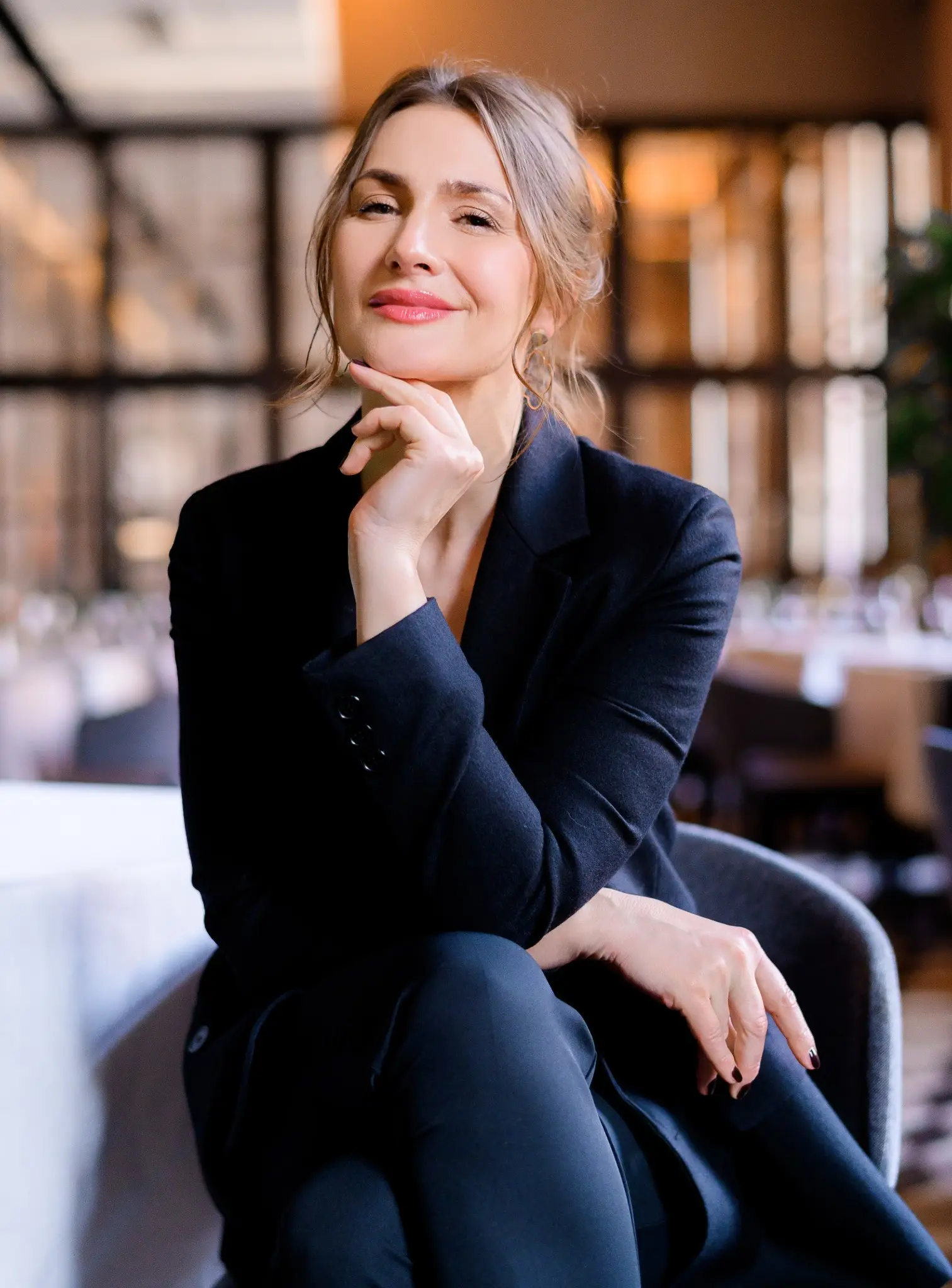 Mulher de negócios confiante em um ambiente de restaurante, sorrindo e refletindo sobre o processo de transformação pessoal.
