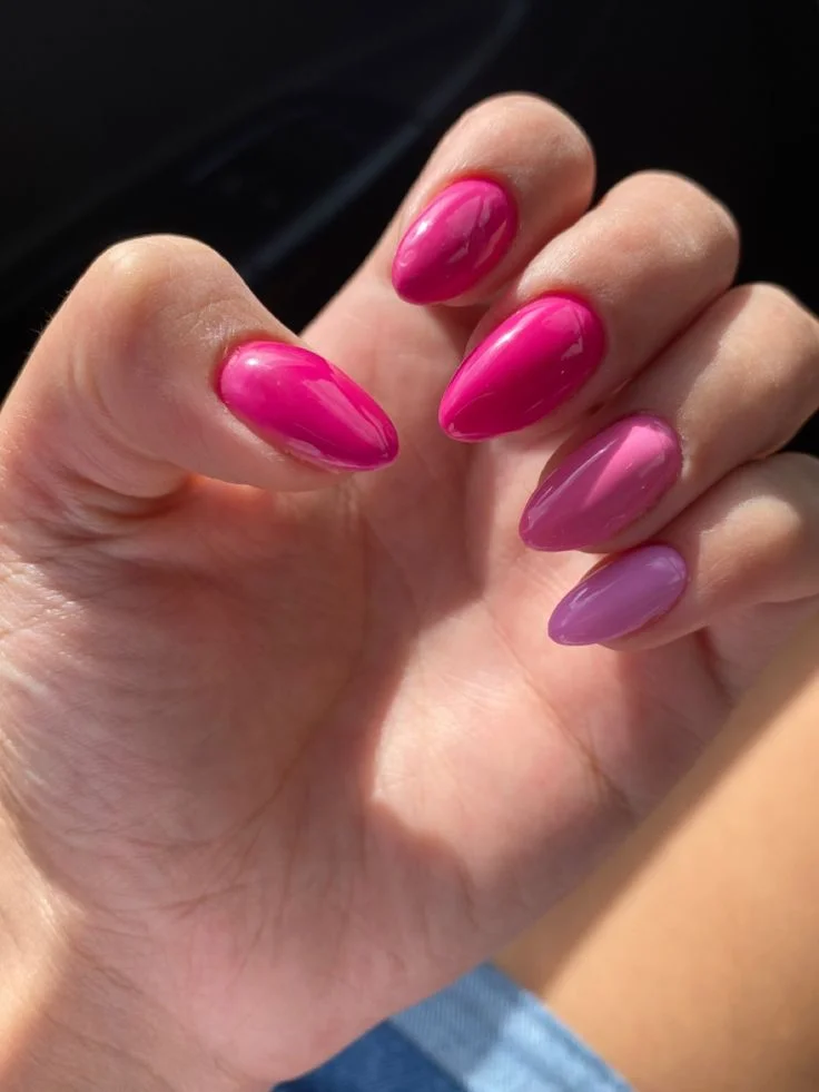 Unhas decoradas com variações de rosa, apresentando um acabamento brilhante e moderno.