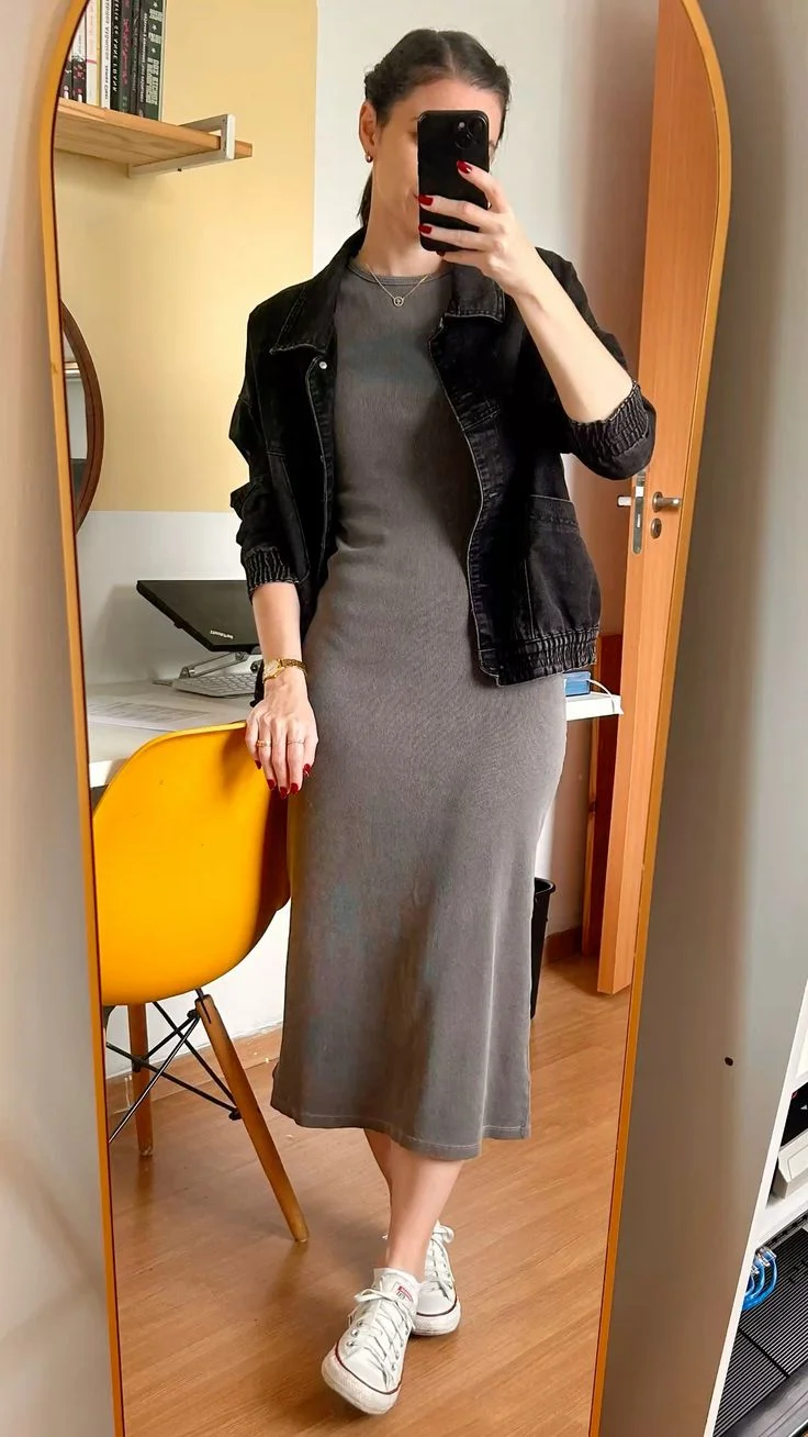 Mulher usando vestido midi cinza com jaqueta jeans e tênis para look home office.