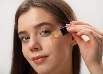 Mulher jovem aplicando óleo de semente de uva na pele, destacando os cuidados com a pele e o uso de produtos naturais.